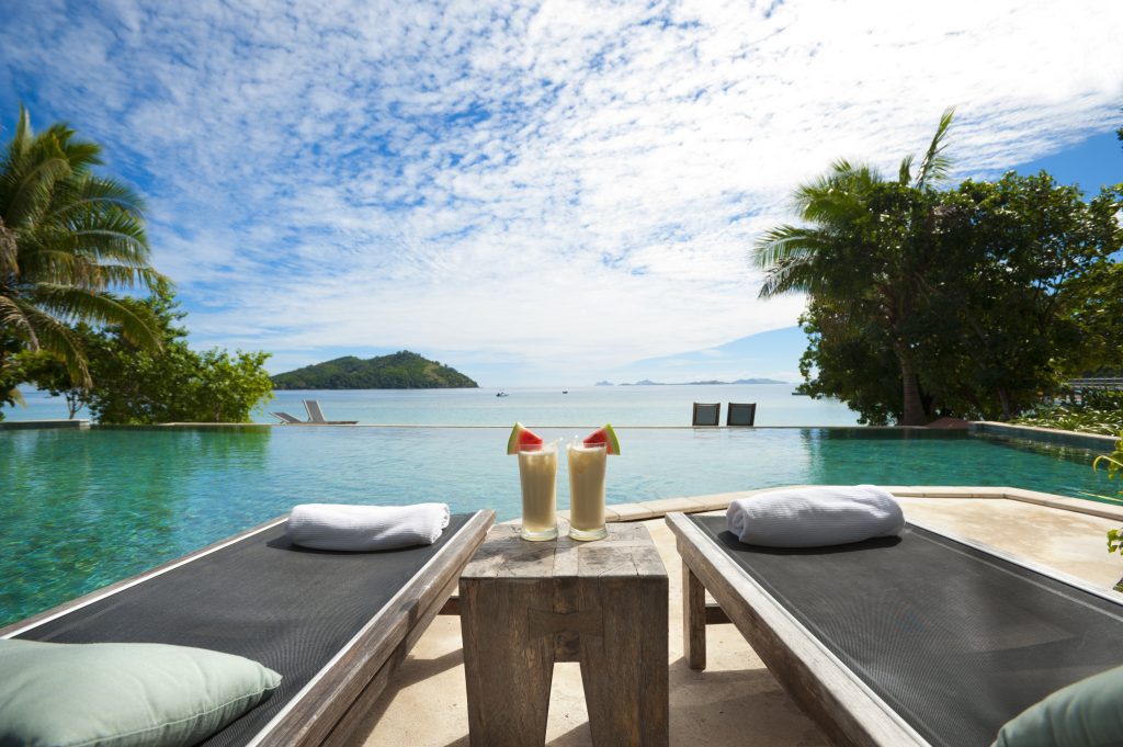 A lounge beside the pool with cocktails on table in Bora Bora