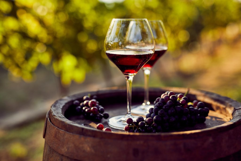 Two glasses of red wine on a wooden barrel in the vineyard - Viking Travel