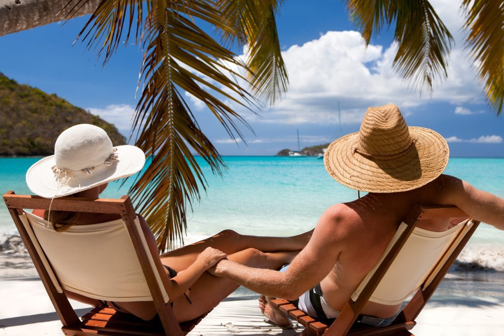 couple holding hands and relaxing at a Caribbean beach on summer enjoying the good weather - Viking Travel