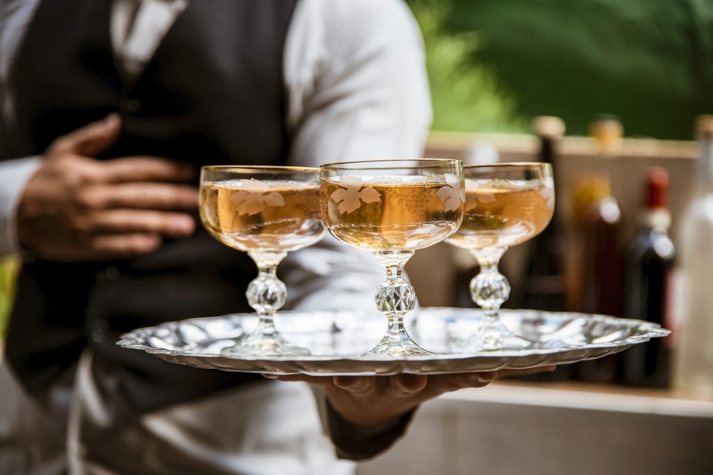 Professional waiter holding a tray with white wine in elegant crystal glasses on Caribbean cruise - Viking Travel