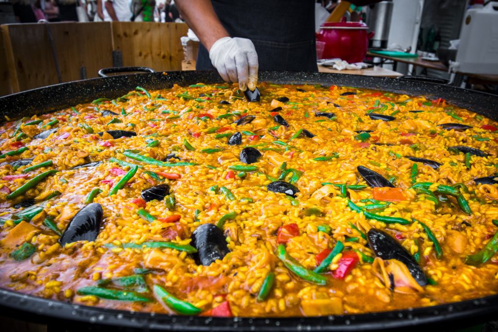 Chef cooking seafood paella on a street food festival - Viking Travel