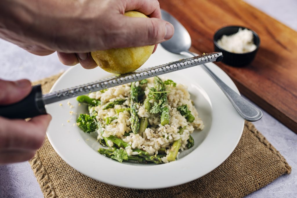 Adding some lemon zest to a dish of asparagus risotto - Viking Travel